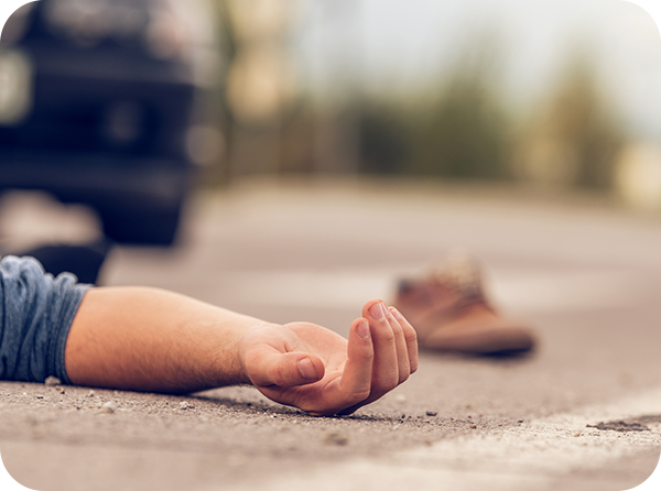 Photo showing an adult laying on the ground with a shoe and car in the background indicating an accident