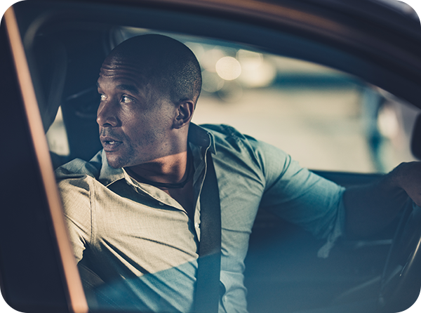 Photo of man in driver's seat looking back over his shoulder as he reverses his car