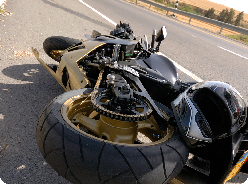 Photo of motorcycle on its side and helmet on the side of the road