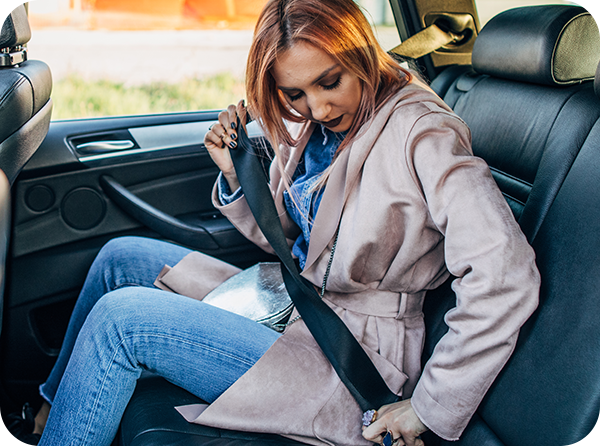 Photo of woman buckling her seat belt in the back seat of a vehicle
