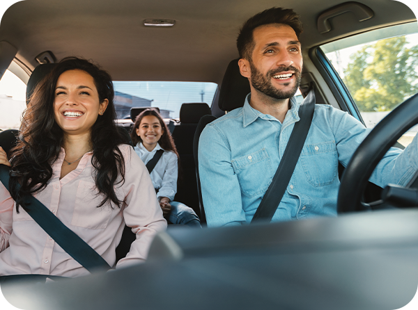 Photo of smiling mom, dad and daughter with their seat belts on in a vehicle