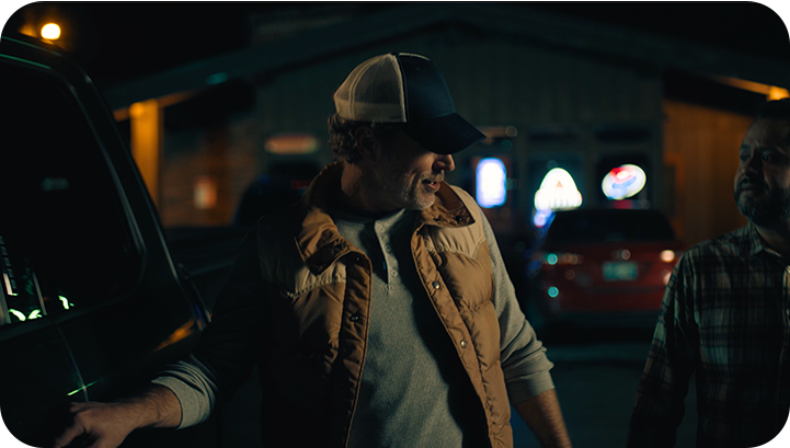 Photo of man reaching for the door handle to open his truck door at night