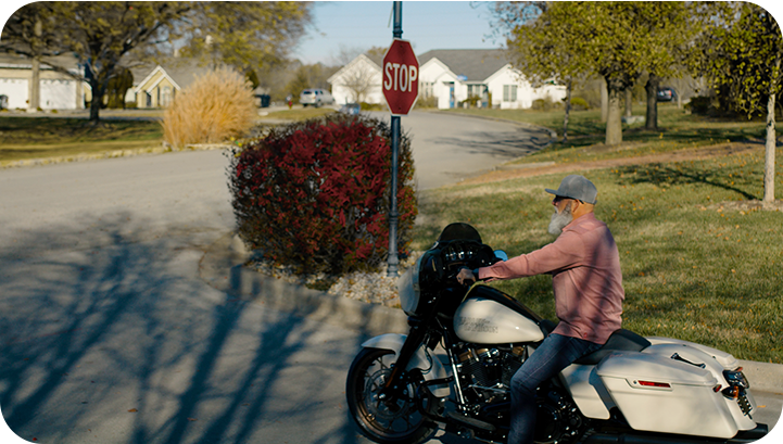Image showing an unhelmeted man on a motorcycle stopped at a stop sign