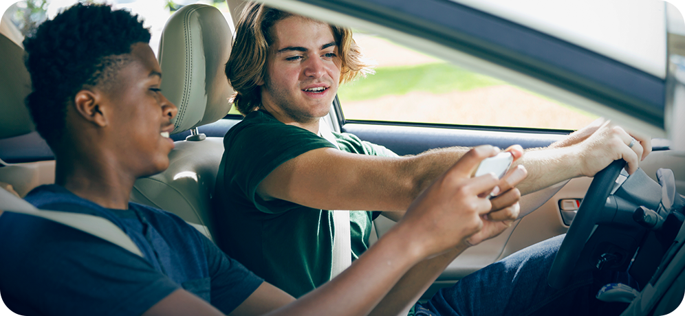 Photo of young driver looking at the phone of a young