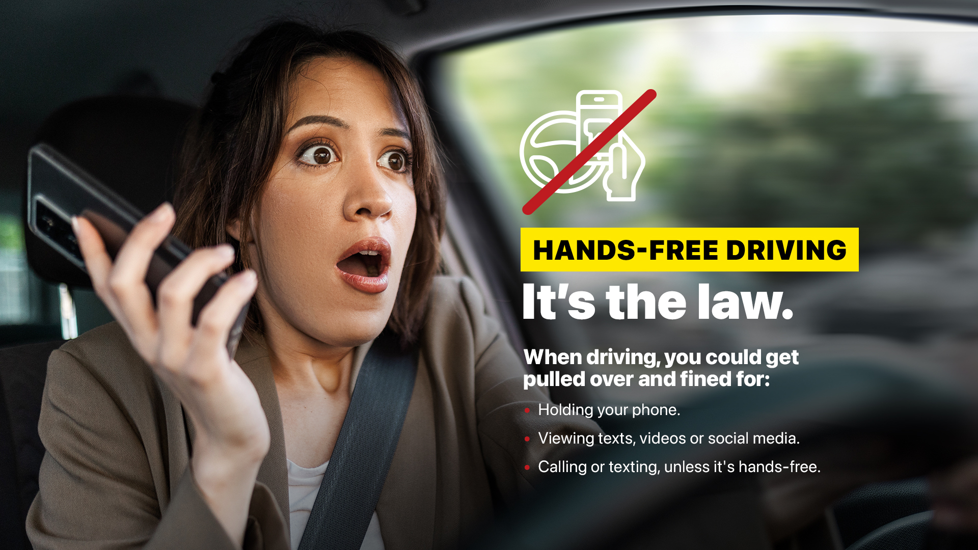 An image of a woman in the driver's seat of a car holding her phone in one hand, looking out the front windshield surprised, with a wheel and phone graphic crossed out over the image and text reading: Hands-free driving. It's the law